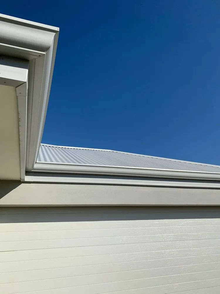 Looking Up at the Roof of a White House With a Blue Sky in the Background — Ron Nickel Roofing in Tweed Heads South, NSW