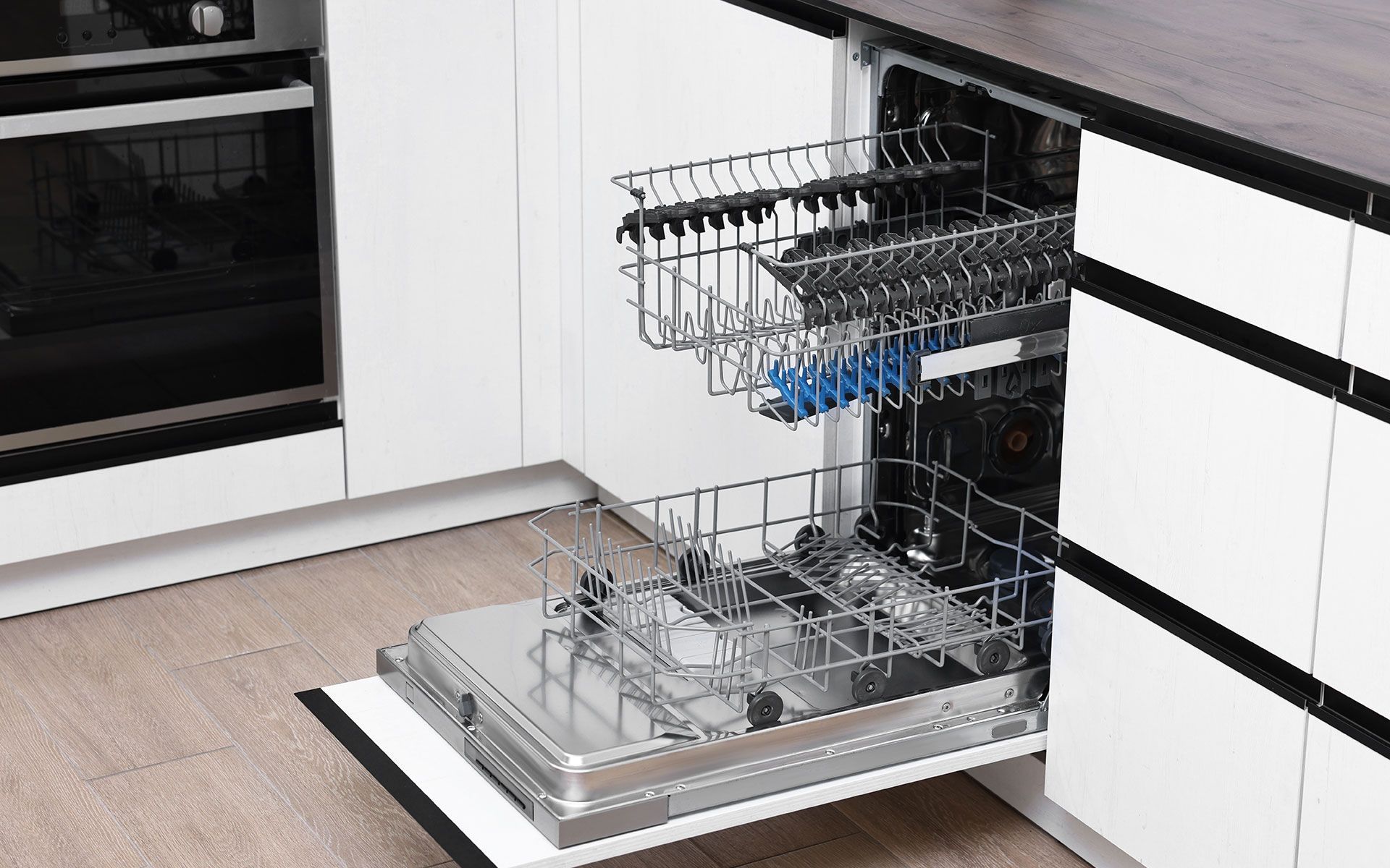Open dishwasher in a modern white kitchen, showing racks and interior.