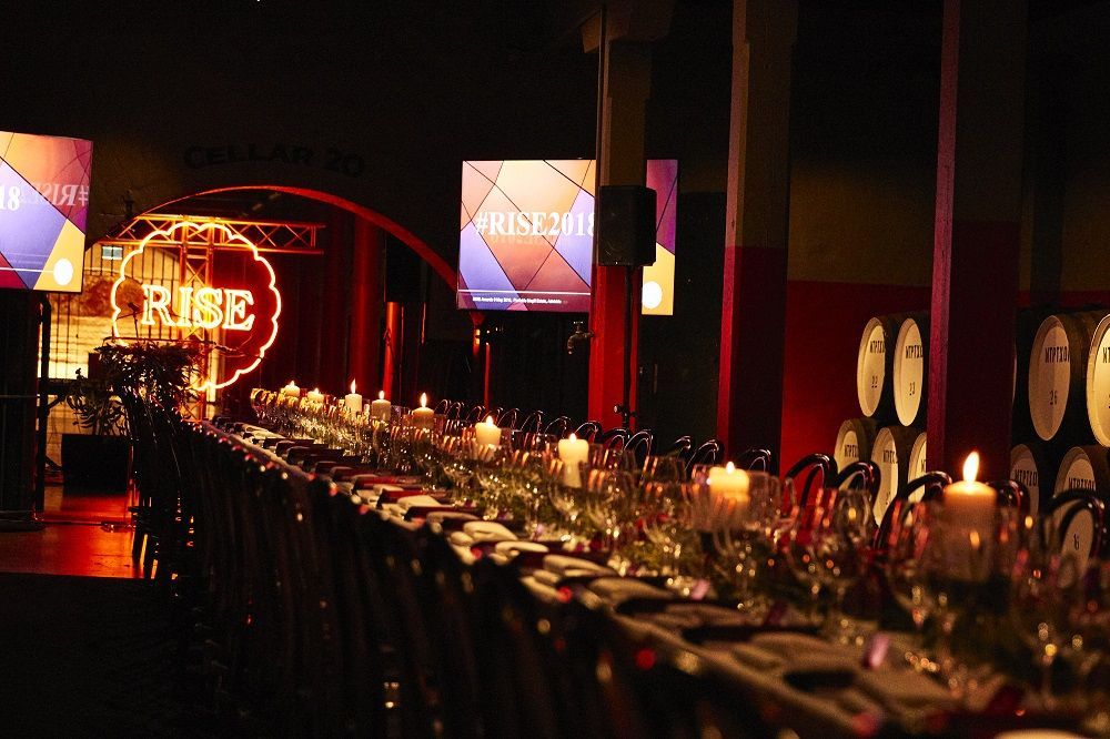 A long table with candles and a sign that says rise