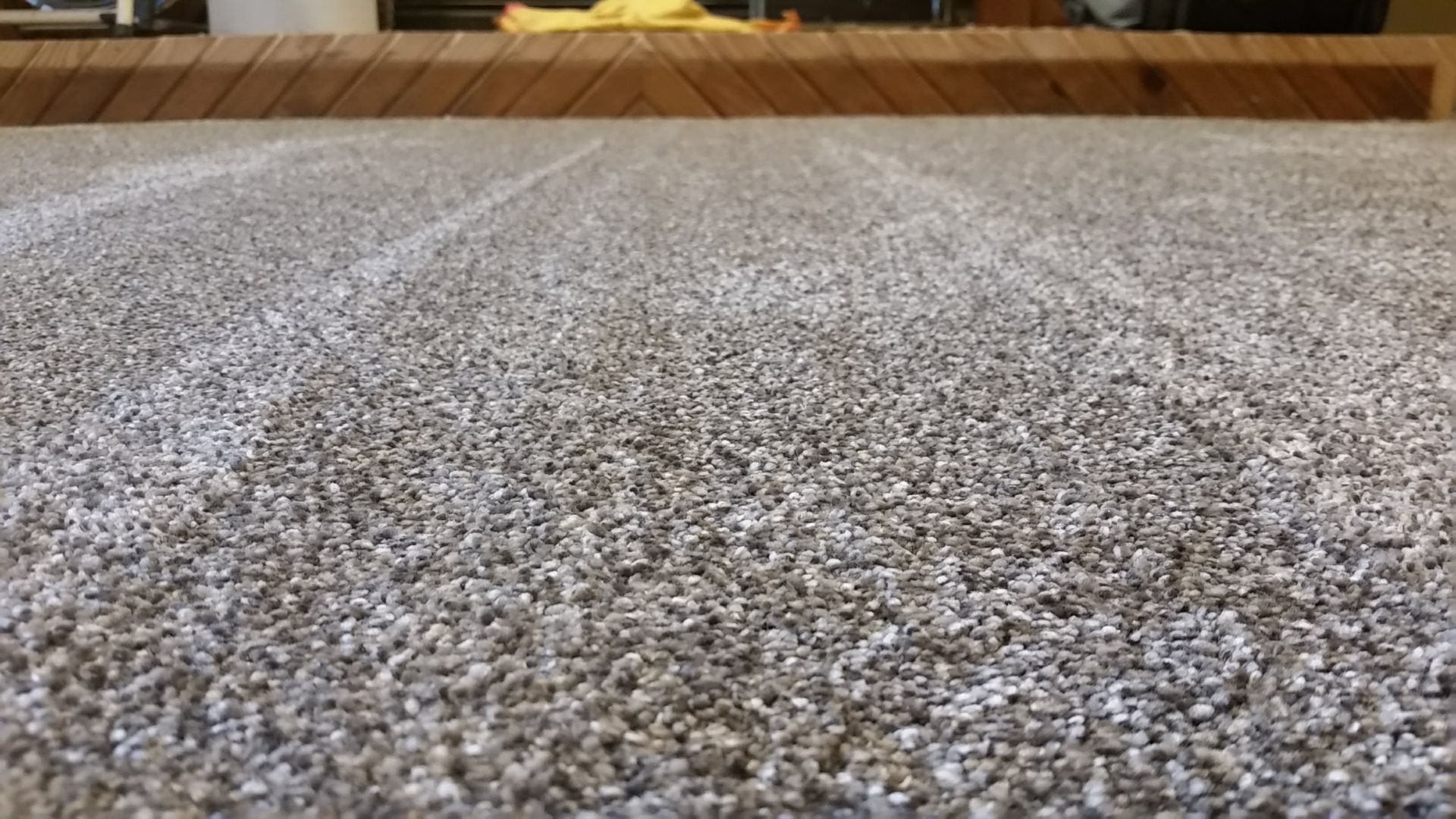 A close up of a carpet with a wooden table in the background.