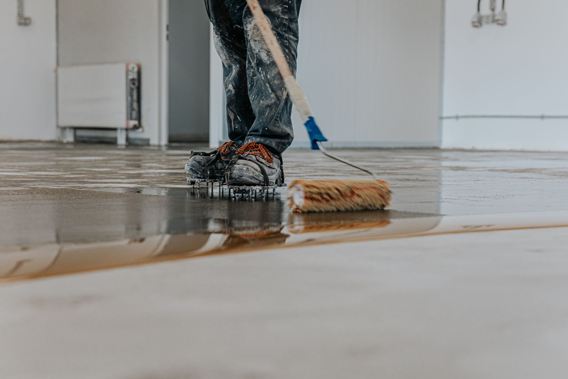 A person is painting a wooden floor with a roller.