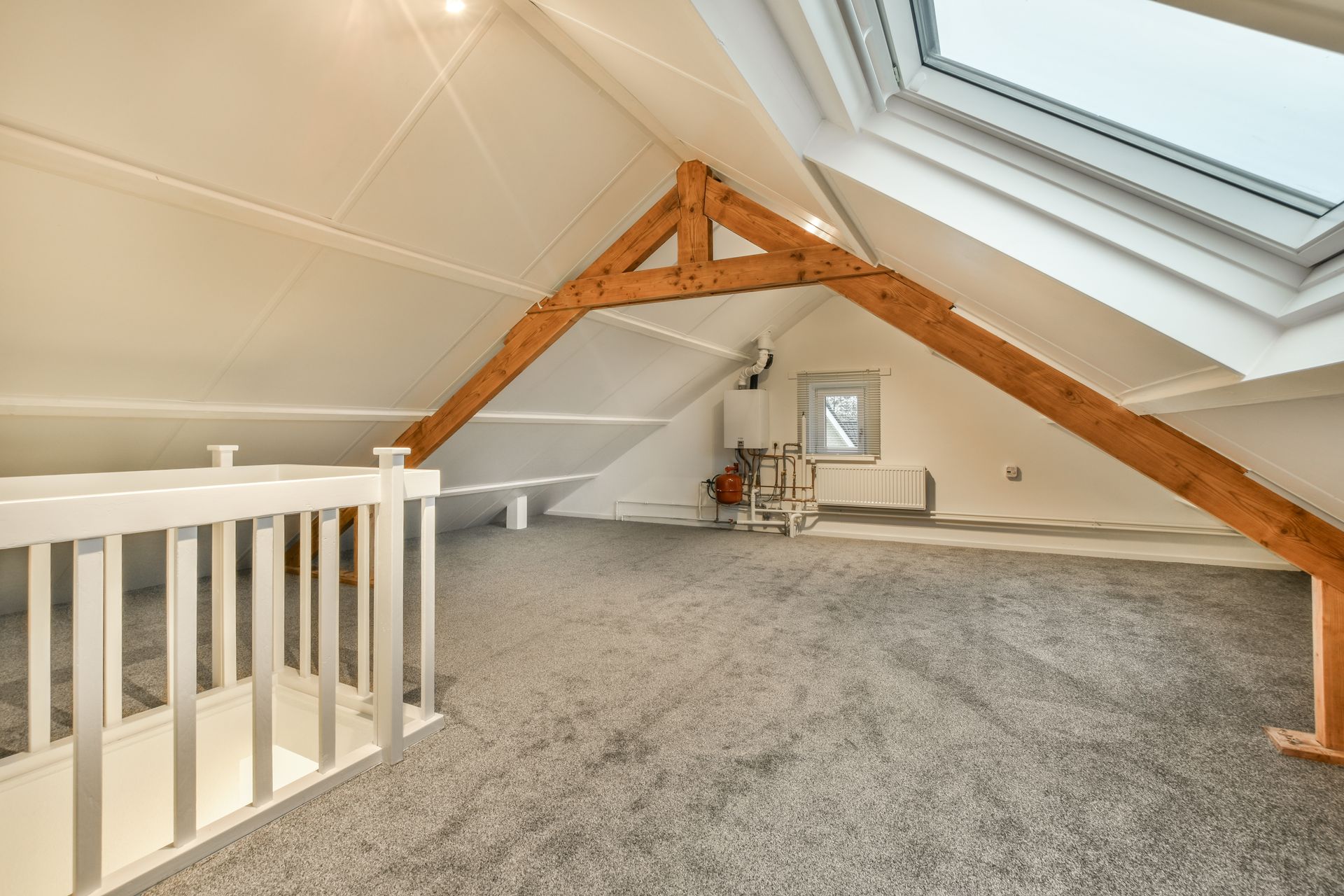 An empty attic with a staircase and a skylight.