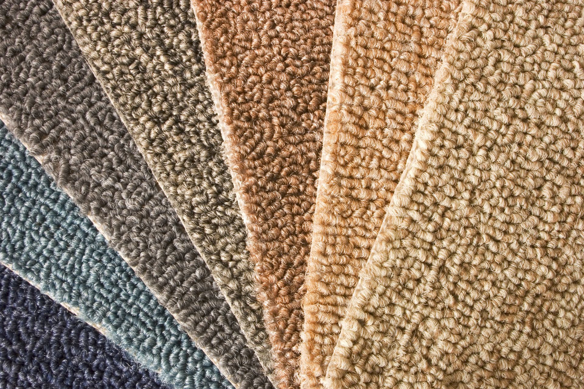 A bunch of different colored carpets are stacked on top of each other.