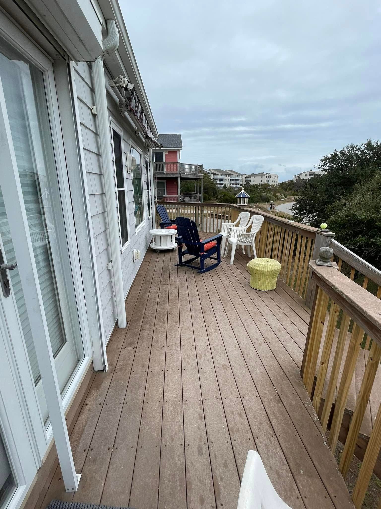A large deck with chairs and a table on it.