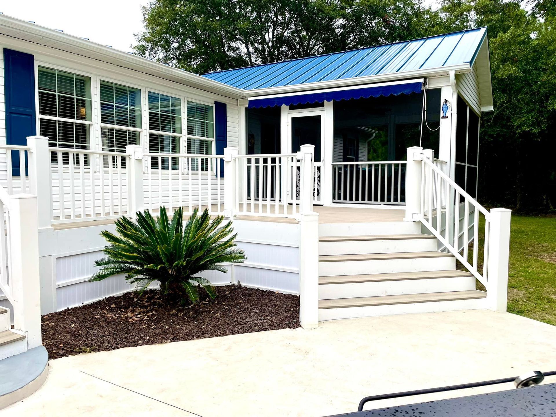 A mobile home with a blue roof and a white porch.