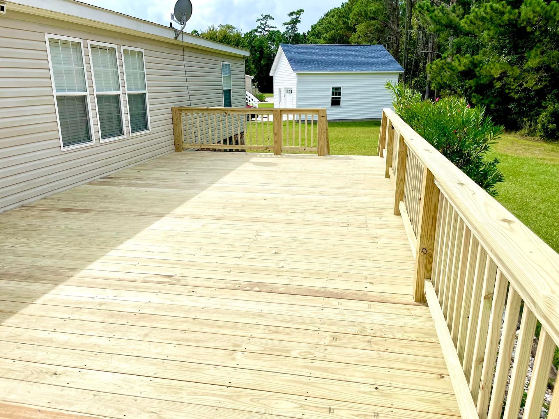 A large wooden deck with a railing in front of a house
