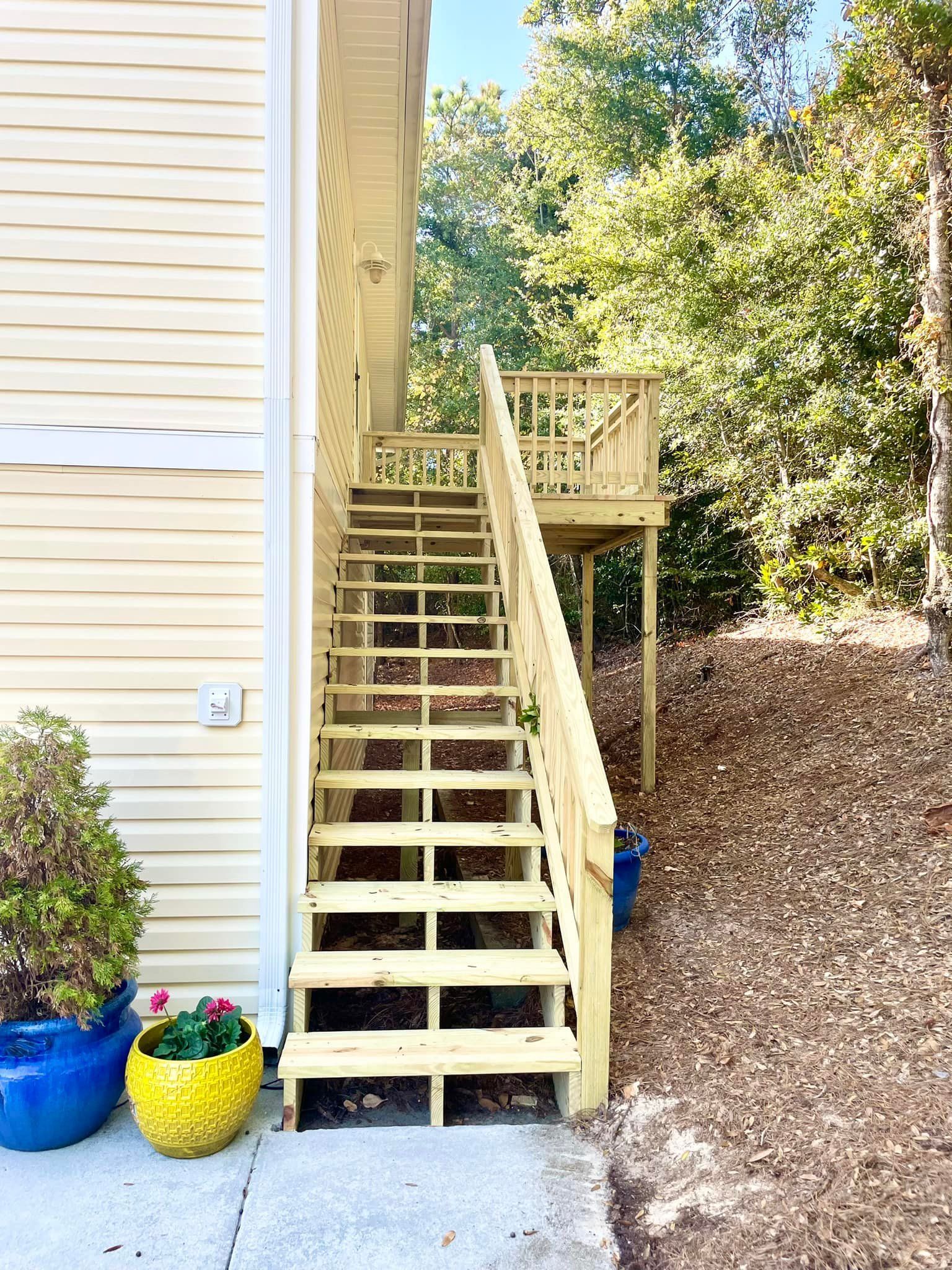 A yellow house with stairs leading up to a deck.