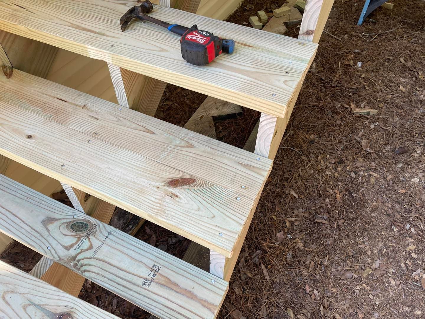 A wooden staircase with a tape measure and hammer on it.