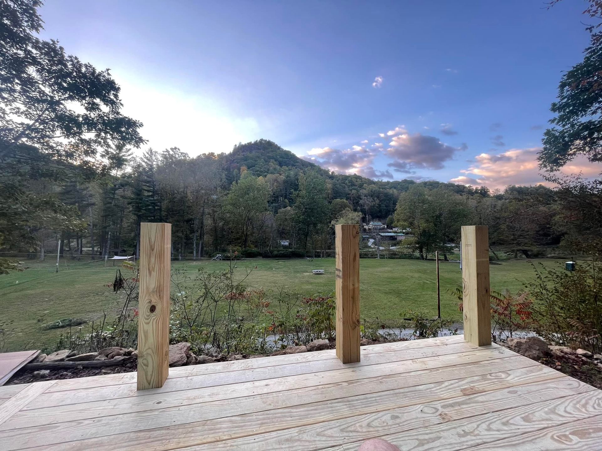 A wooden deck with a view of a field and mountains in the background.