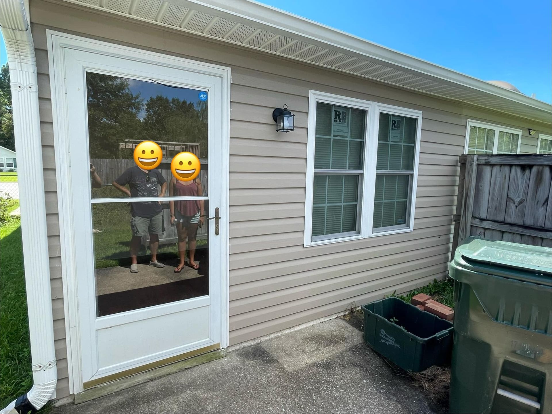 A couple of people standing in front of a house with smiley faces on their faces.