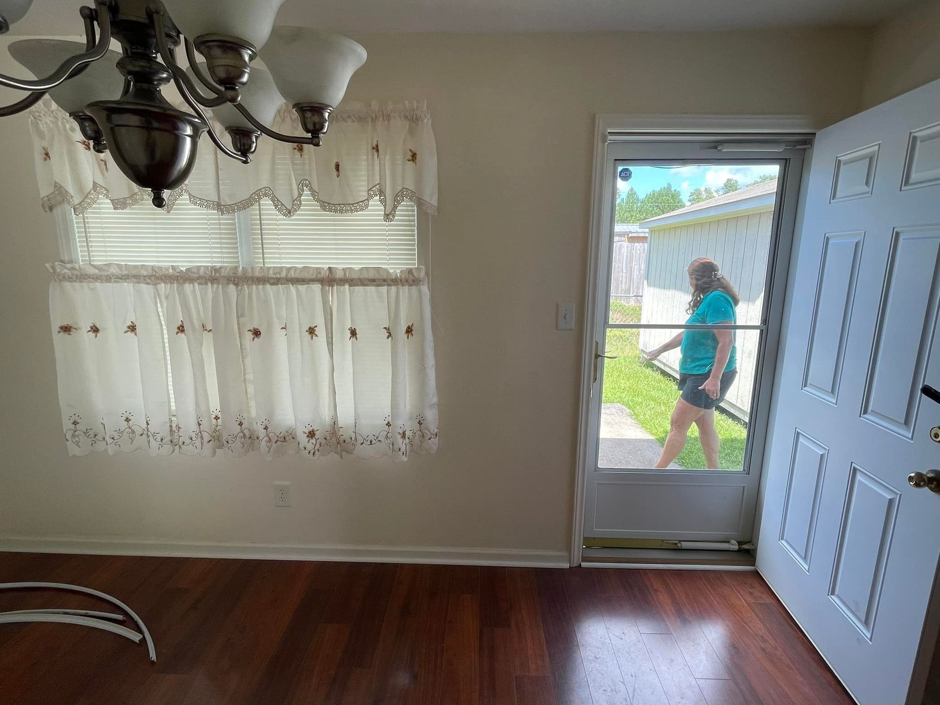 A woman is standing in front of a door in an empty room.
