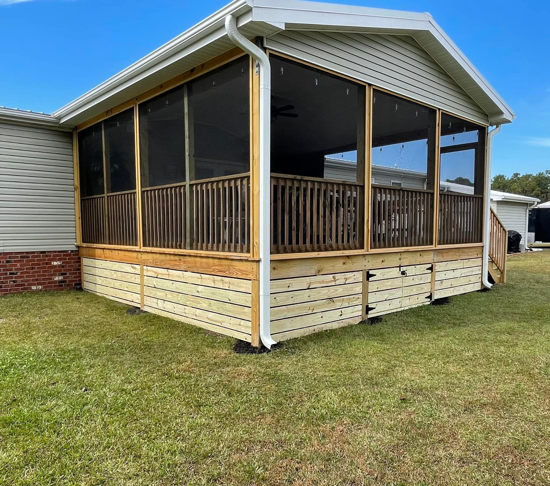 A mobile home with a screened in porch in front of it.