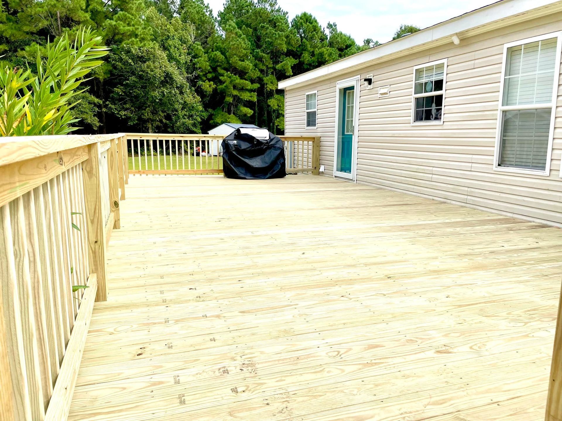 A mobile home with a large wooden deck in front of it.