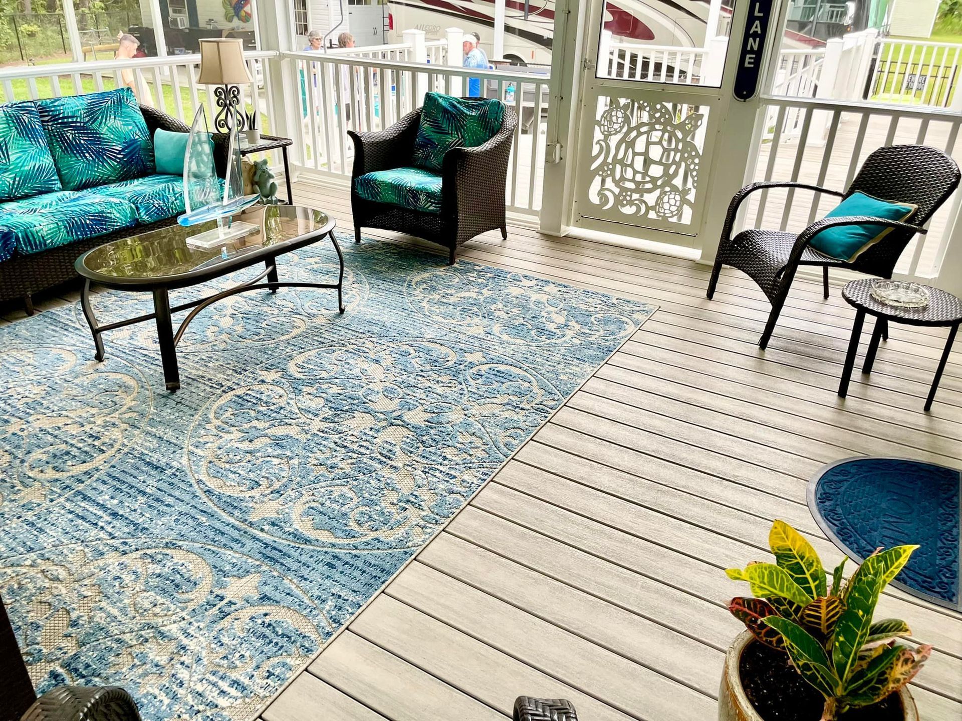 A porch with a couch , chairs , tables and a rug.