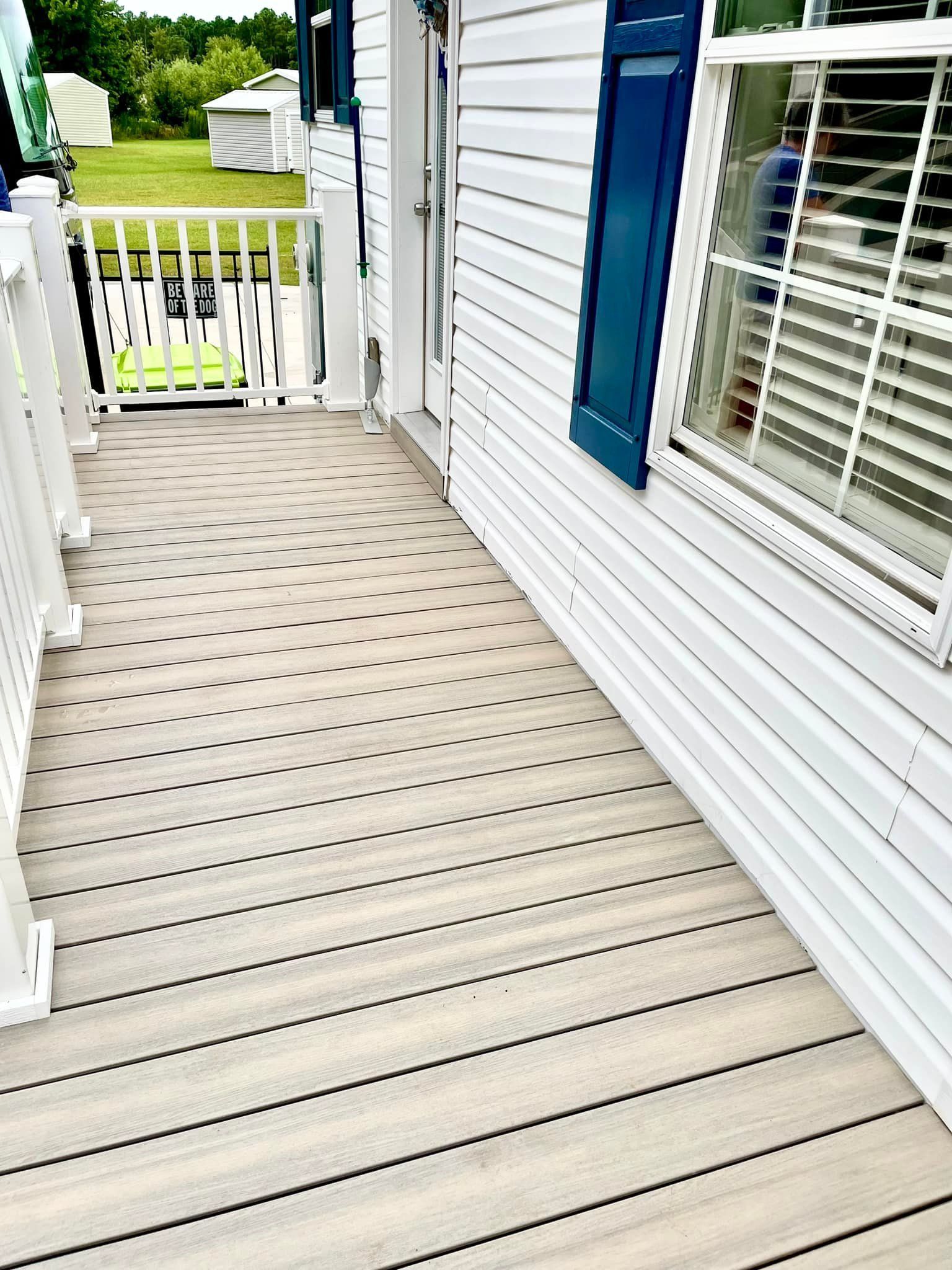 A white house with a wooden deck and blue shutters.