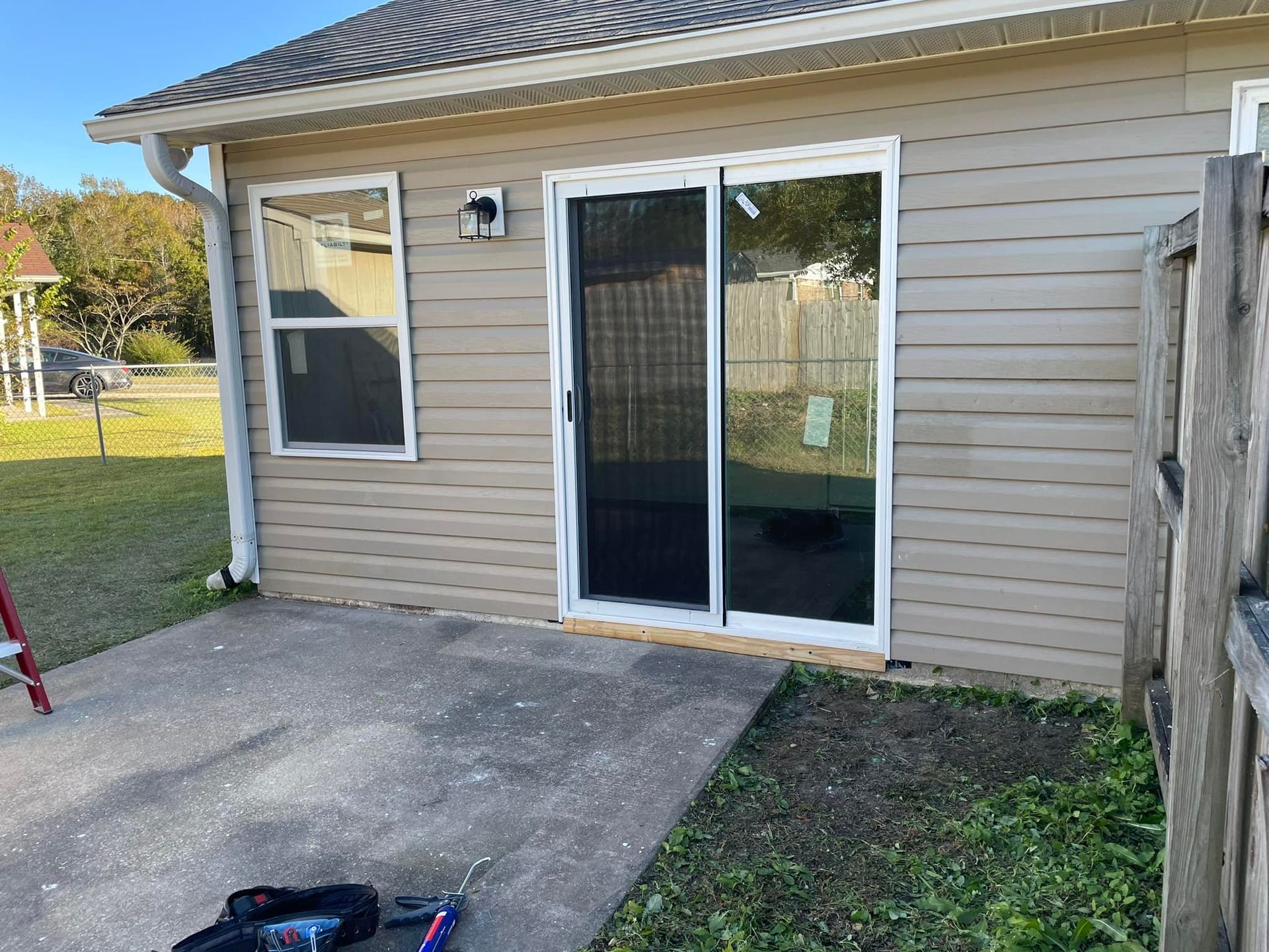 A house with a sliding glass door and a ladder in front of it.