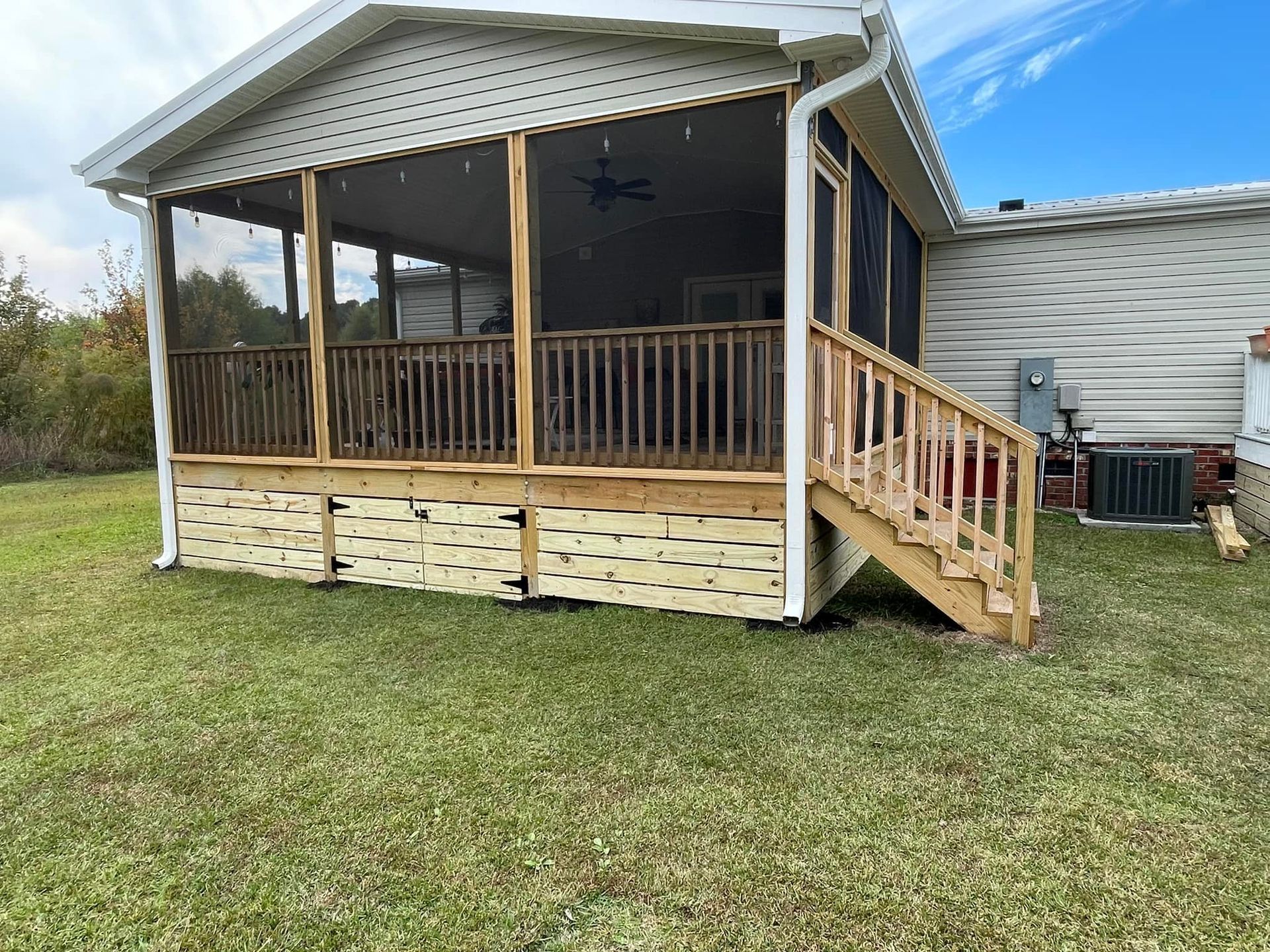 A mobile home with a screened in porch and stairs.