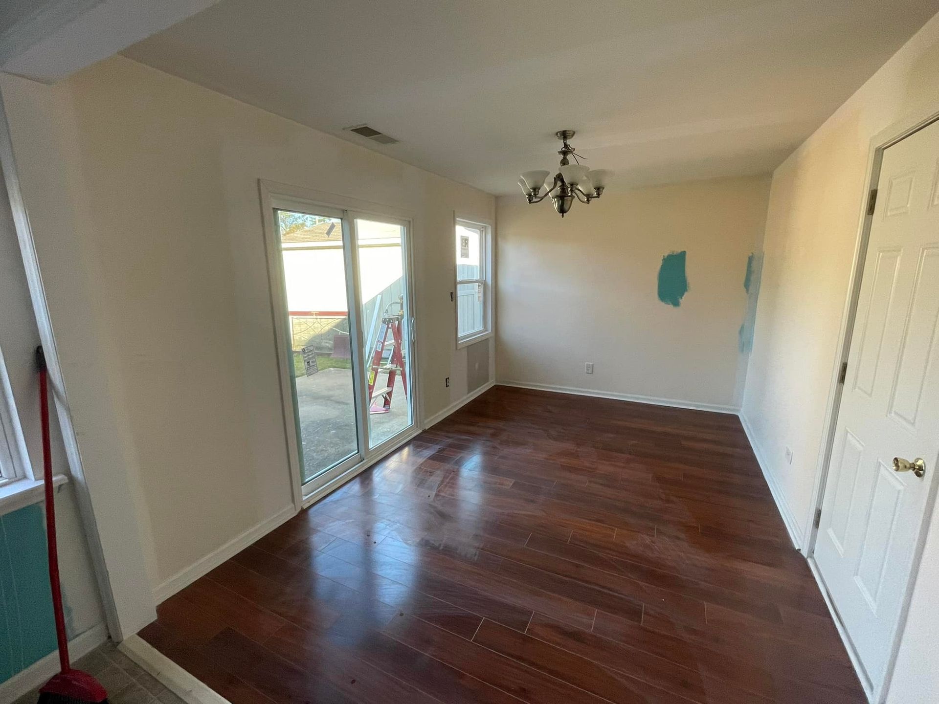 An empty living room with hardwood floors , white walls and sliding glass doors.