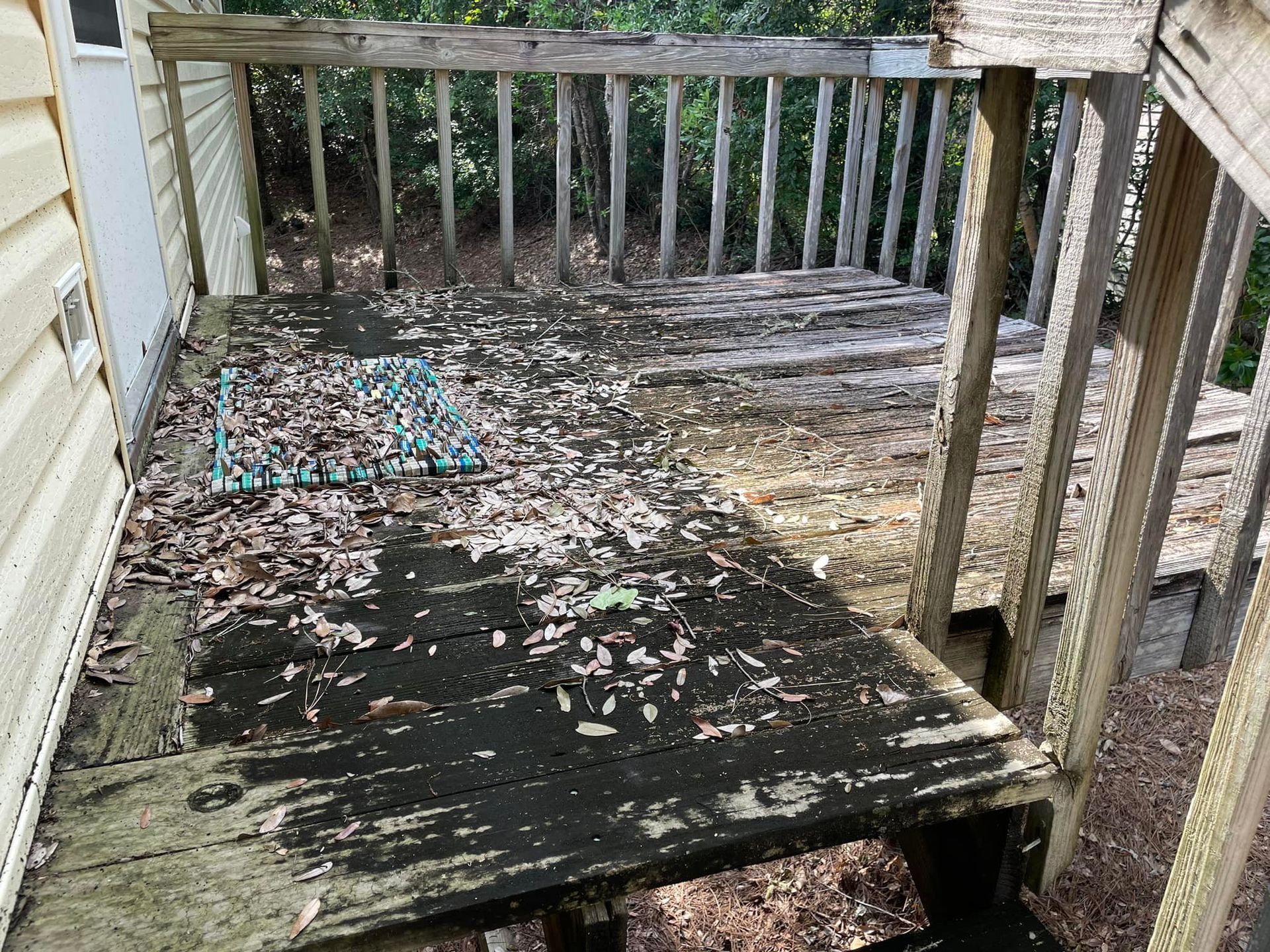 A wooden deck with a rug on it is sitting in front of a house.