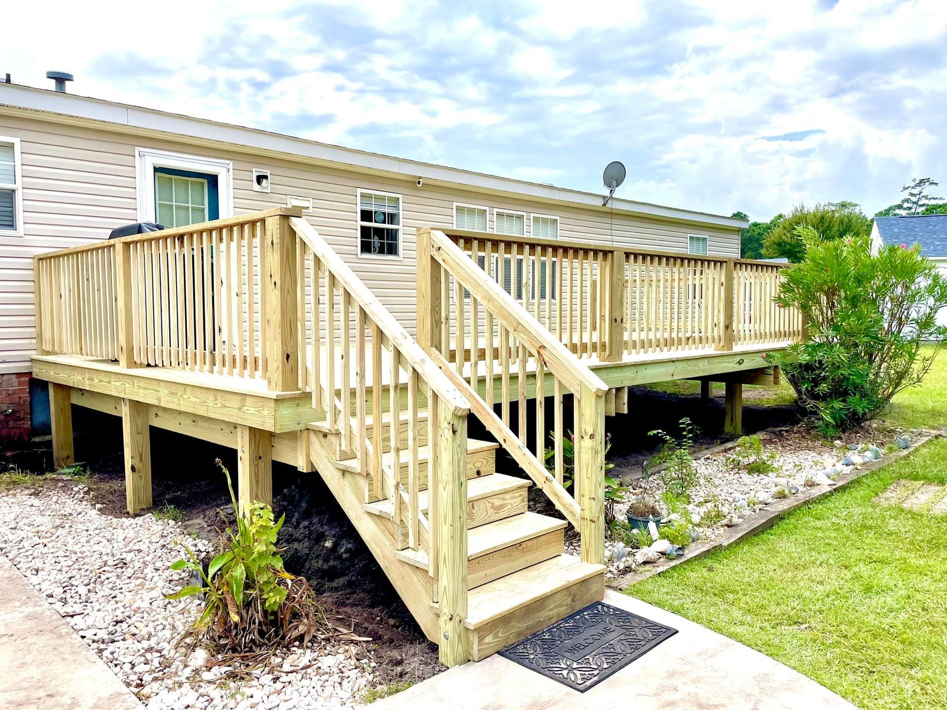 A mobile home with a wooden deck and stairs in front of it.