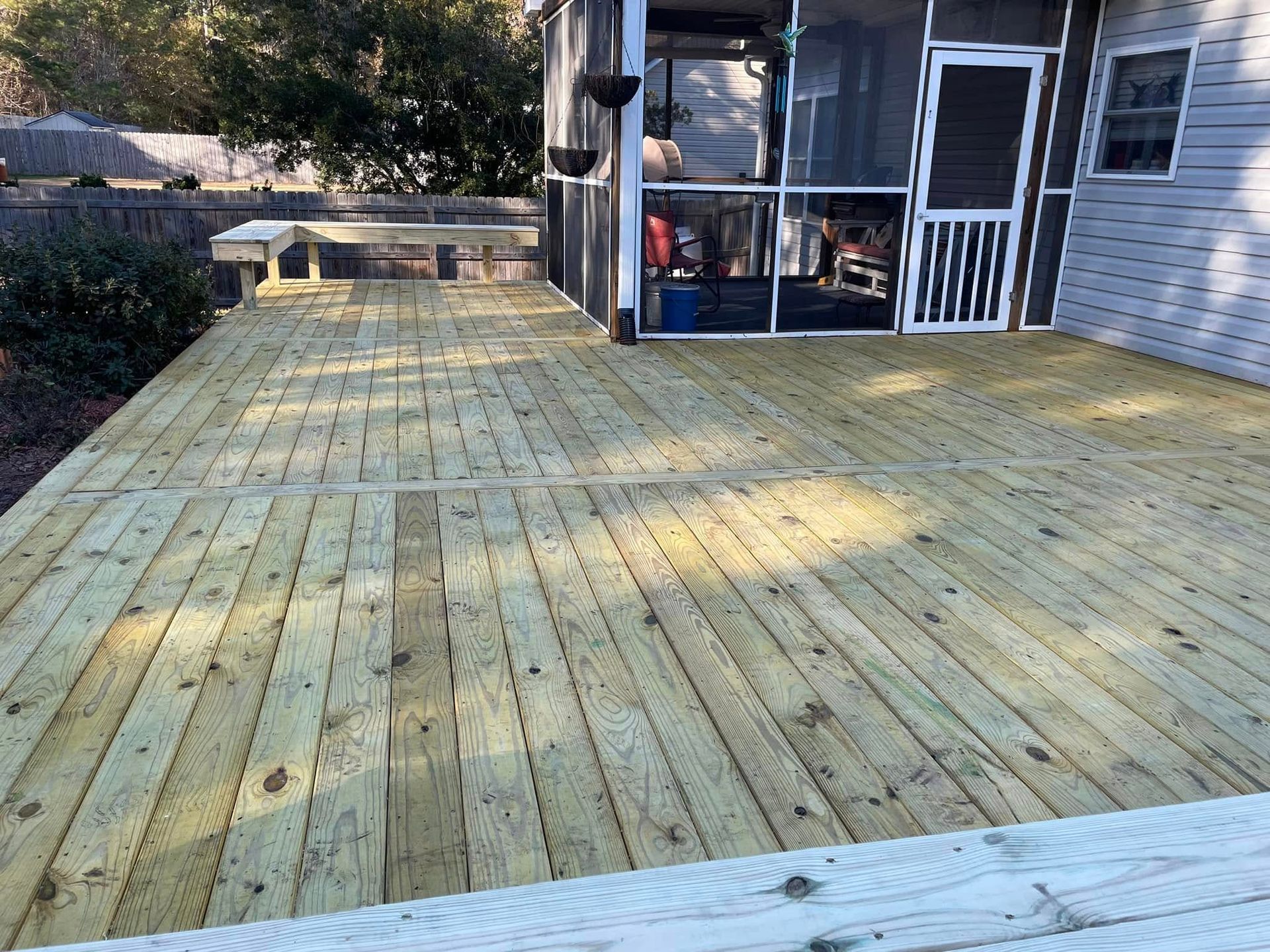A wooden deck with a screened in porch next to a house.