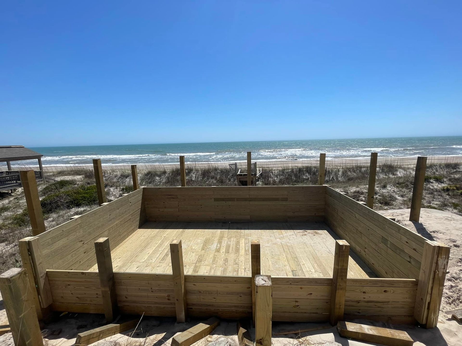 A large wooden structure is being built on the beach.