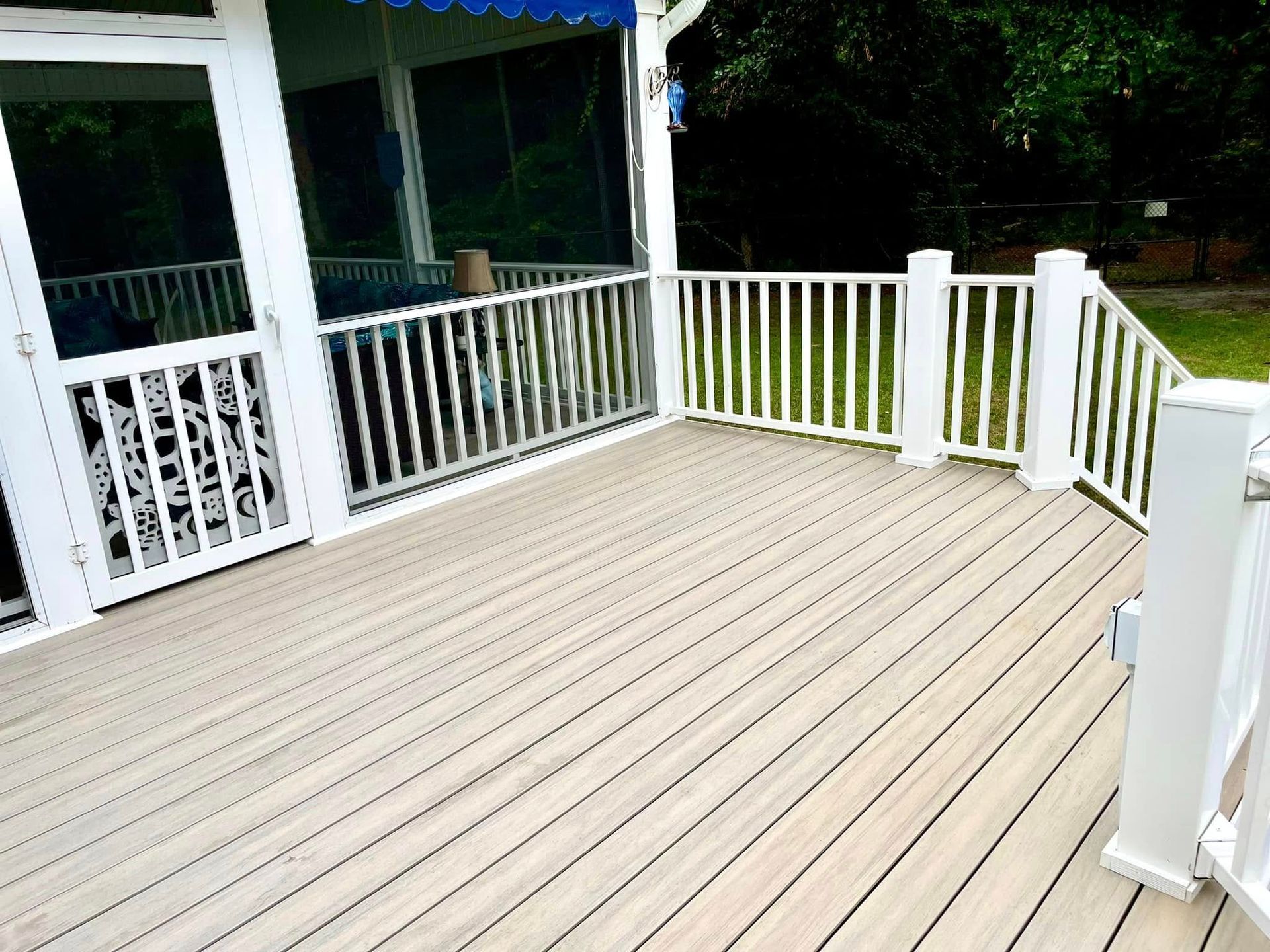 A deck with a screened in porch and a white railing.