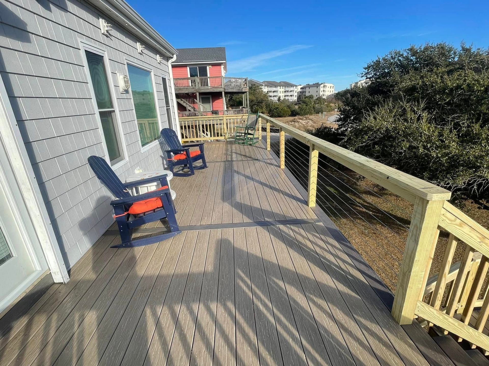 There are two chairs on the deck of a house.