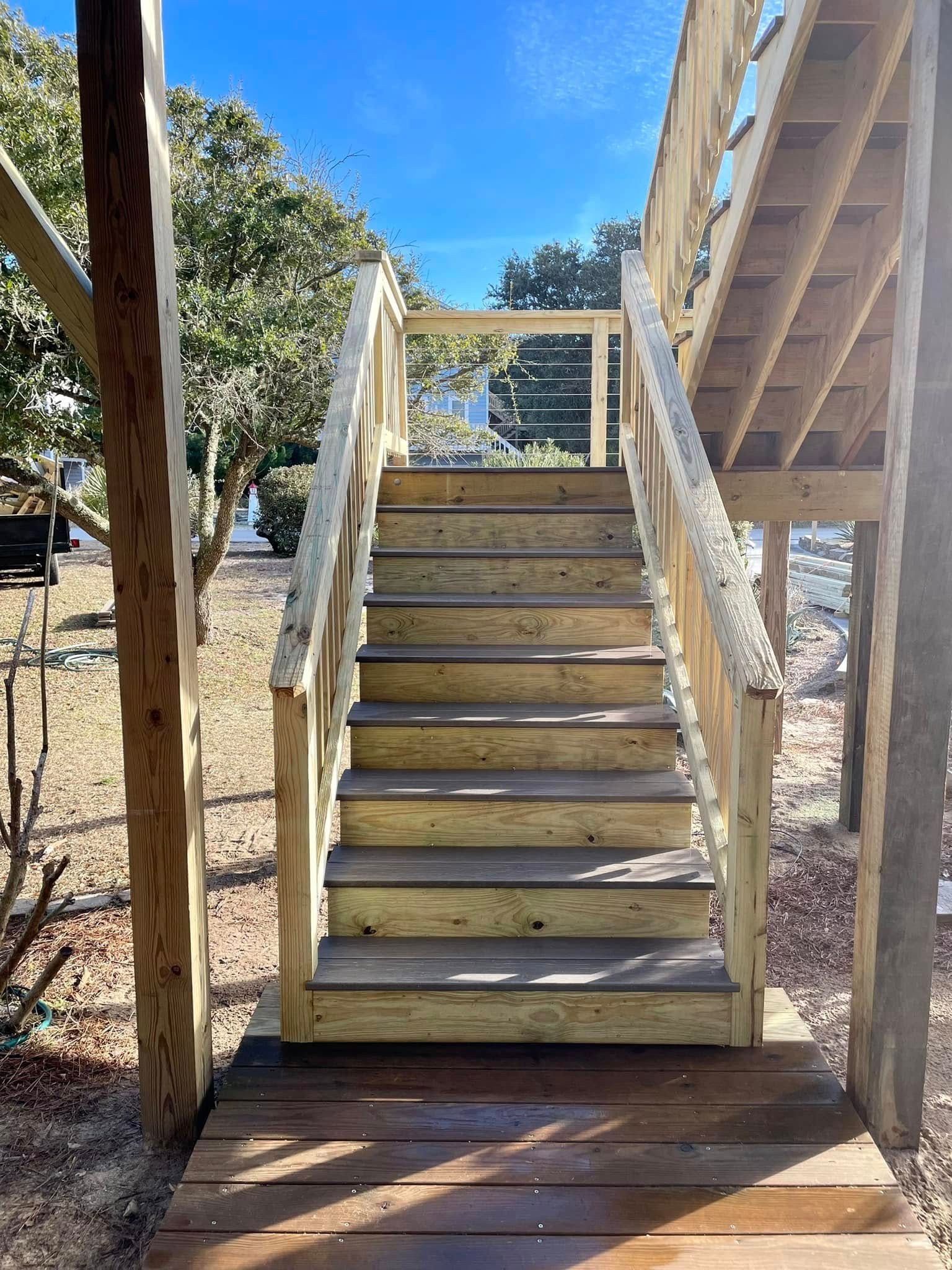 A set of wooden stairs leading up to a wooden deck.