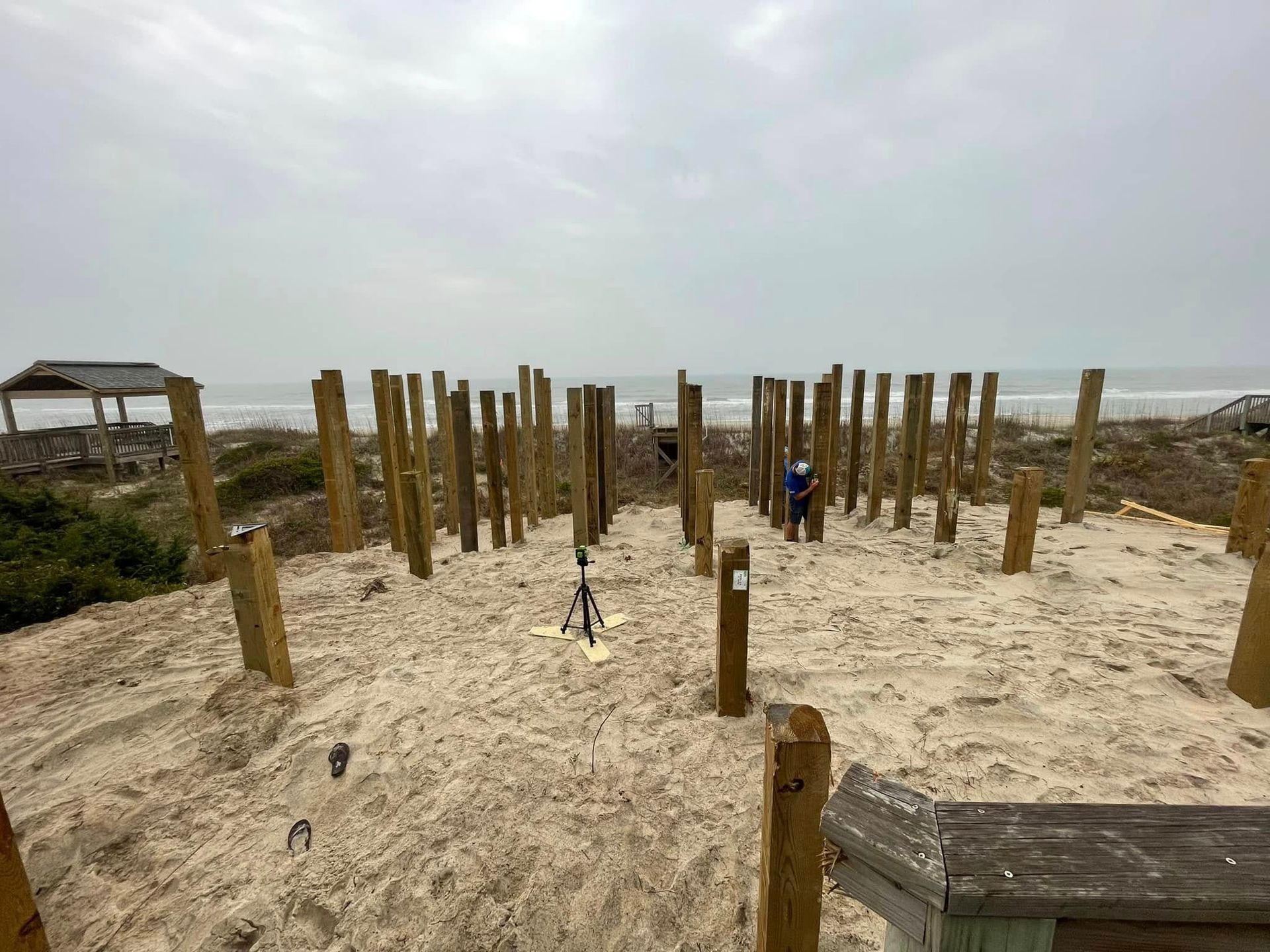 A group of wooden posts sitting on top of a sandy beach.
