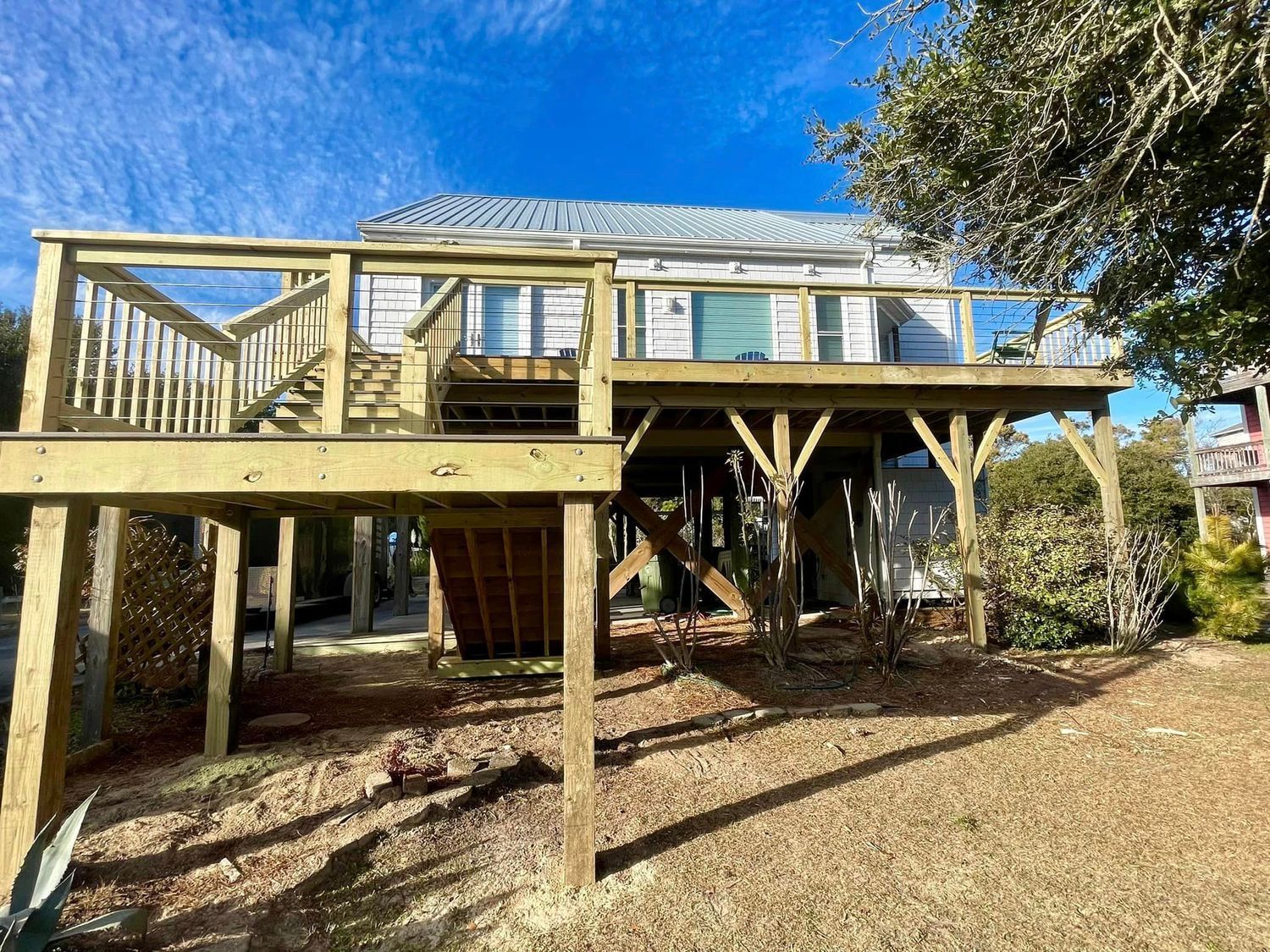 A house with a large wooden deck on top of it.