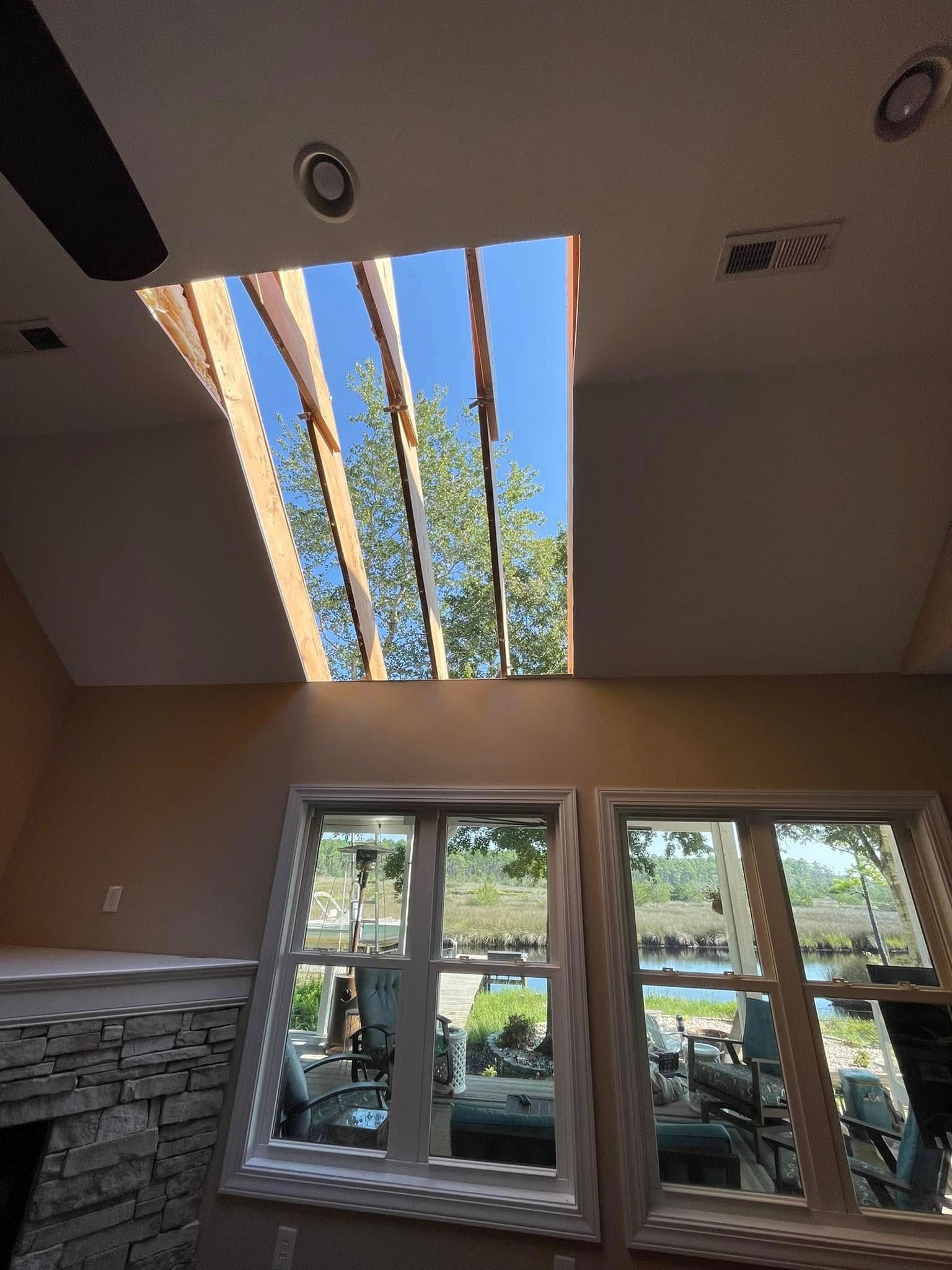 A living room with a skylight in the ceiling and a fireplace.