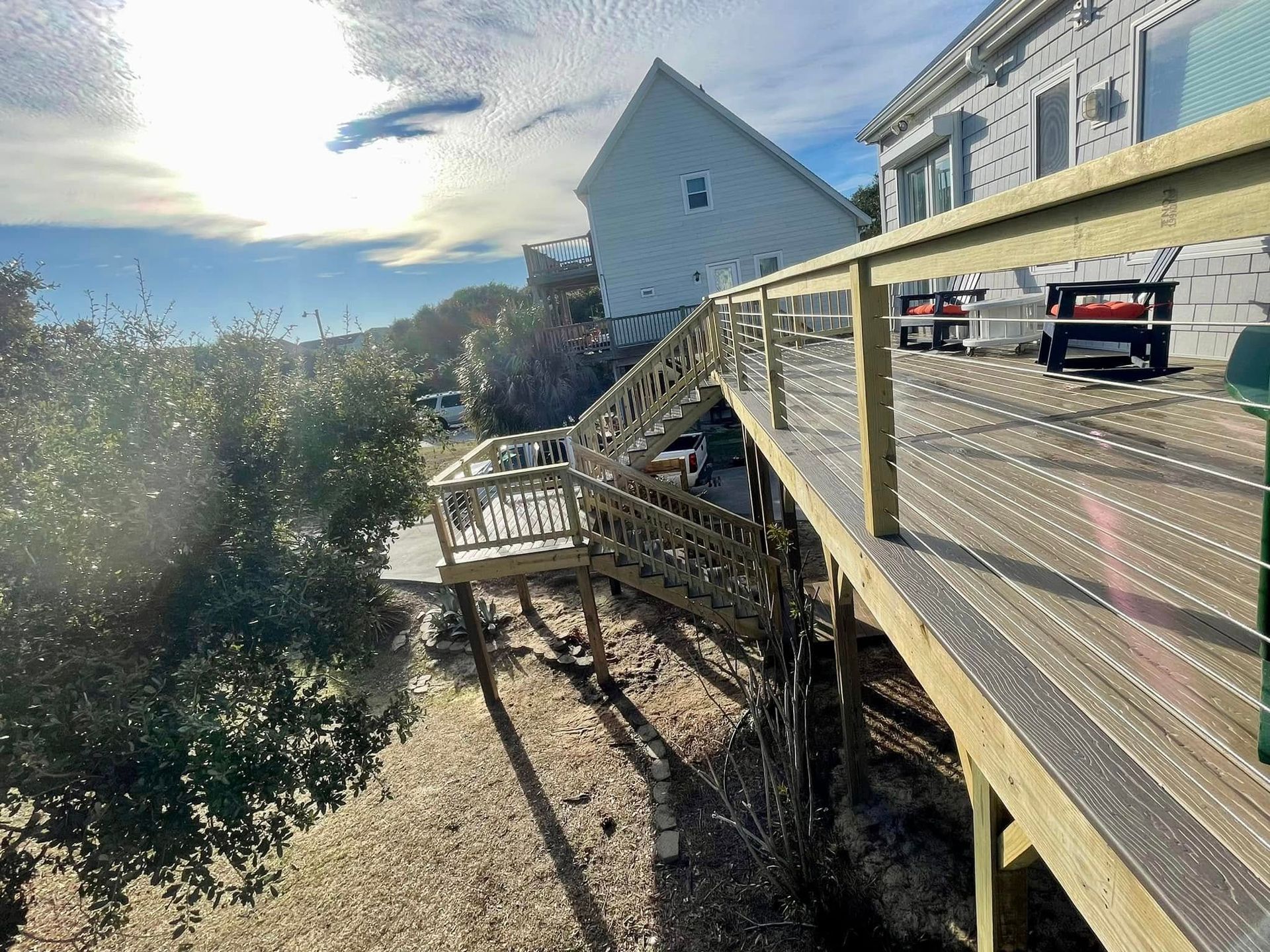 A wooden deck with stairs leading up to a white house.