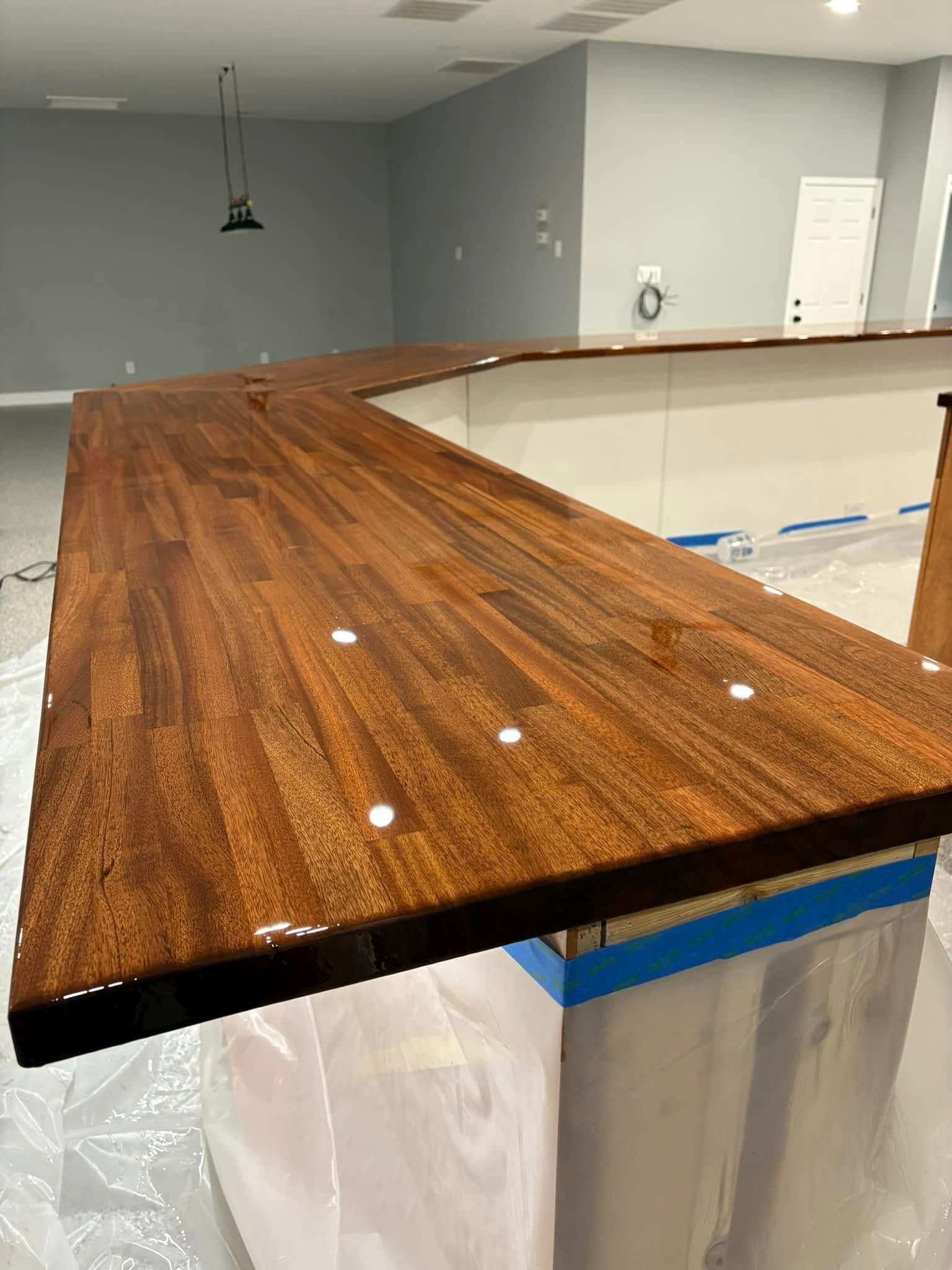 A wooden counter top is being painted in a kitchen.