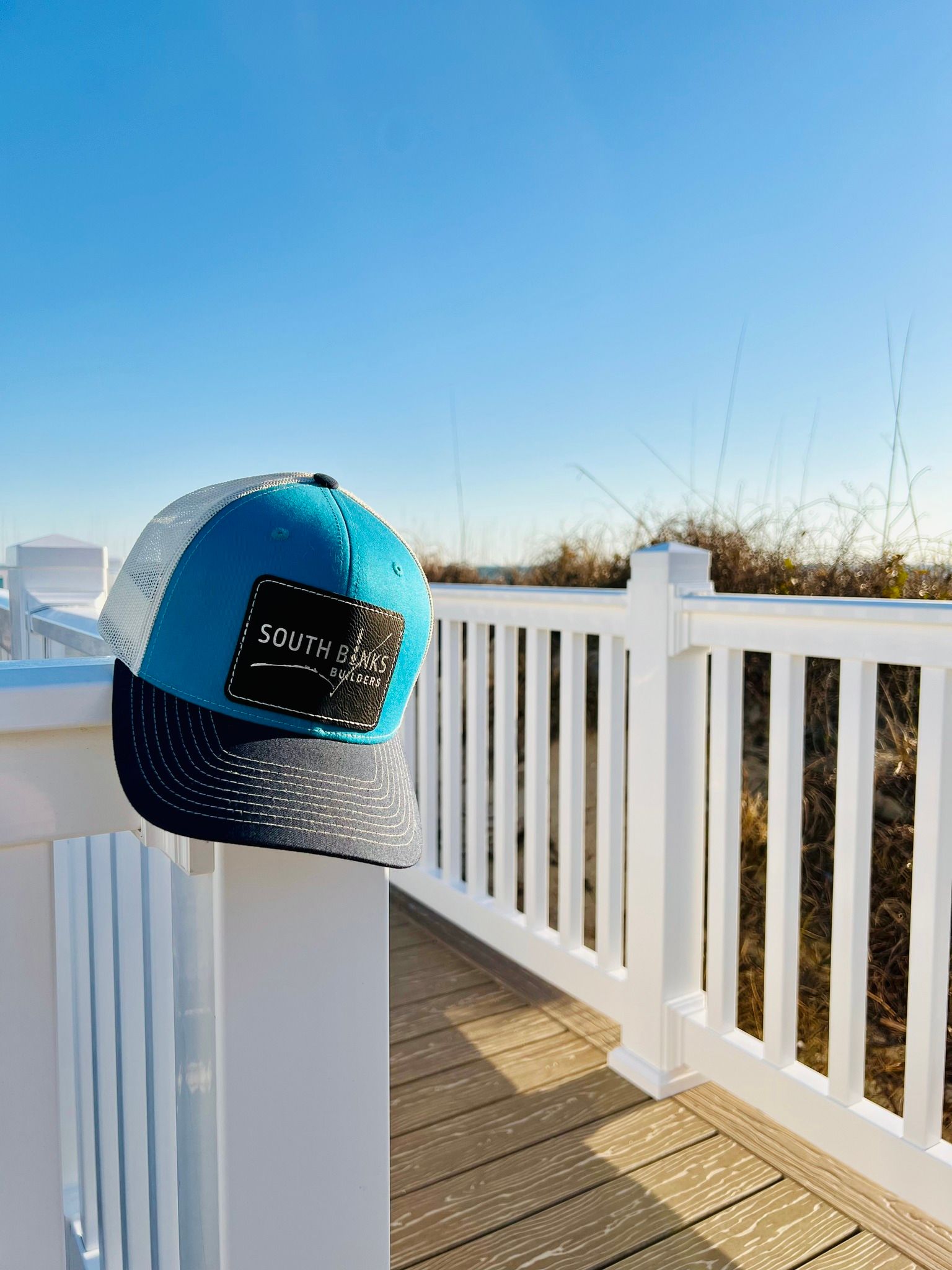 A blue hat is sitting on top of a white railing.