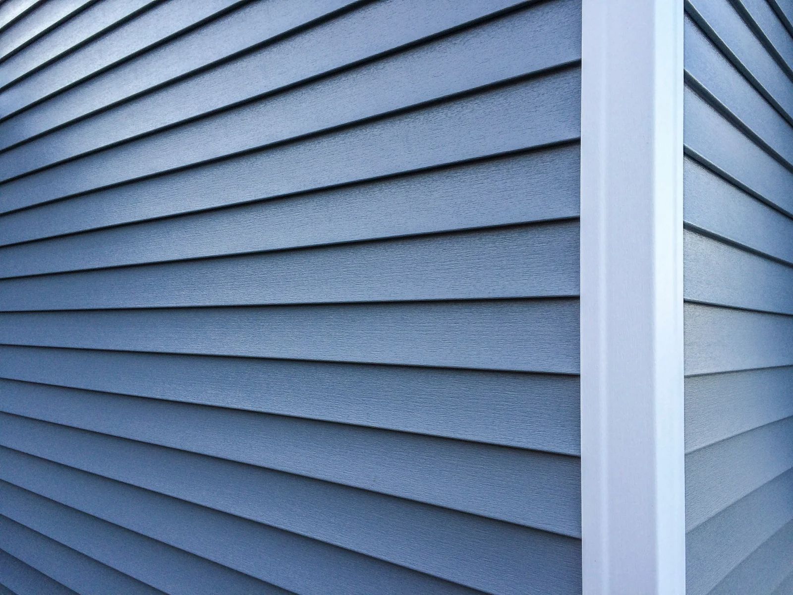 A close up of a blue siding on a house with a white trim