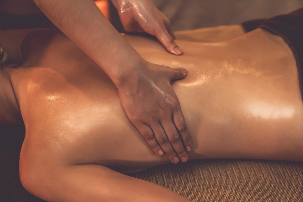 Persona recibiendo un masaje de espalda con una vara de bambú.