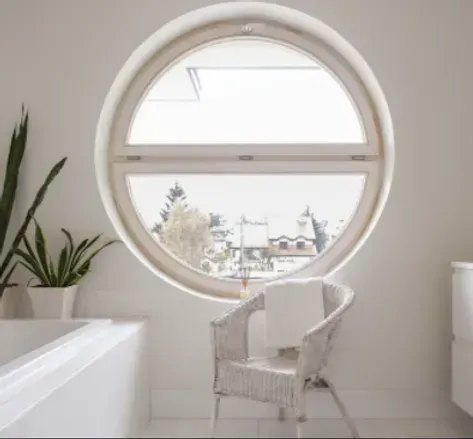 Finestra rotonda nel bagno bianco con vista sulla città e sedia in vimini.