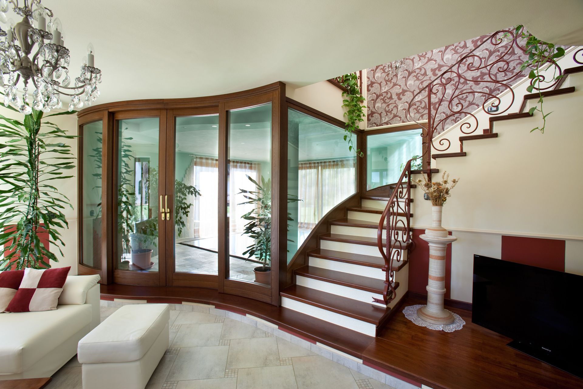 Soggiorno con parete in vetro curva, scala e divano bianco.