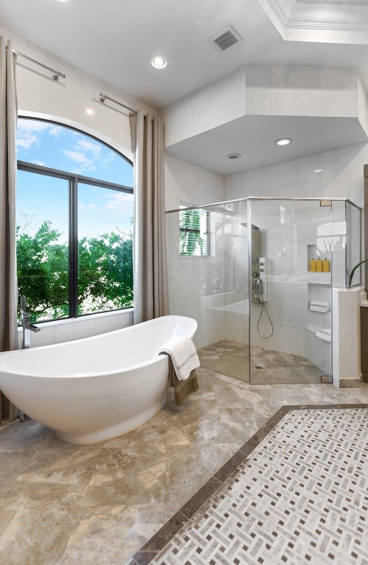 Lussuoso bagno con vasca indipendente, ampia finestra e box doccia in vetro.