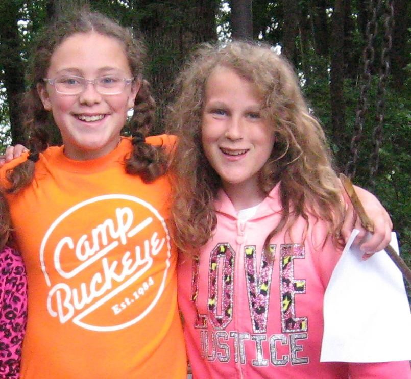Two girls wearing camp buckeye shirts are posing for a picture