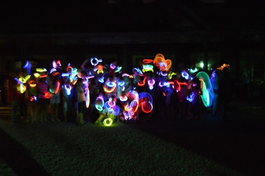 A group of people are standing in a dark room with glow in the dark lights.