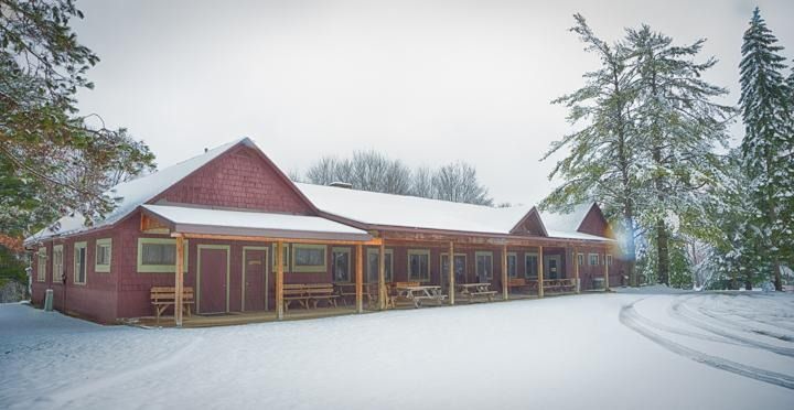 A red building with a porch is covered in snow.