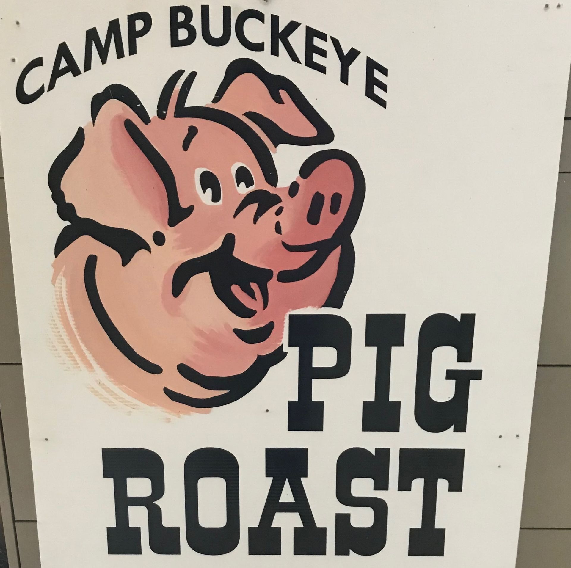 A sign for camp buckeye pig roast with a pig on it