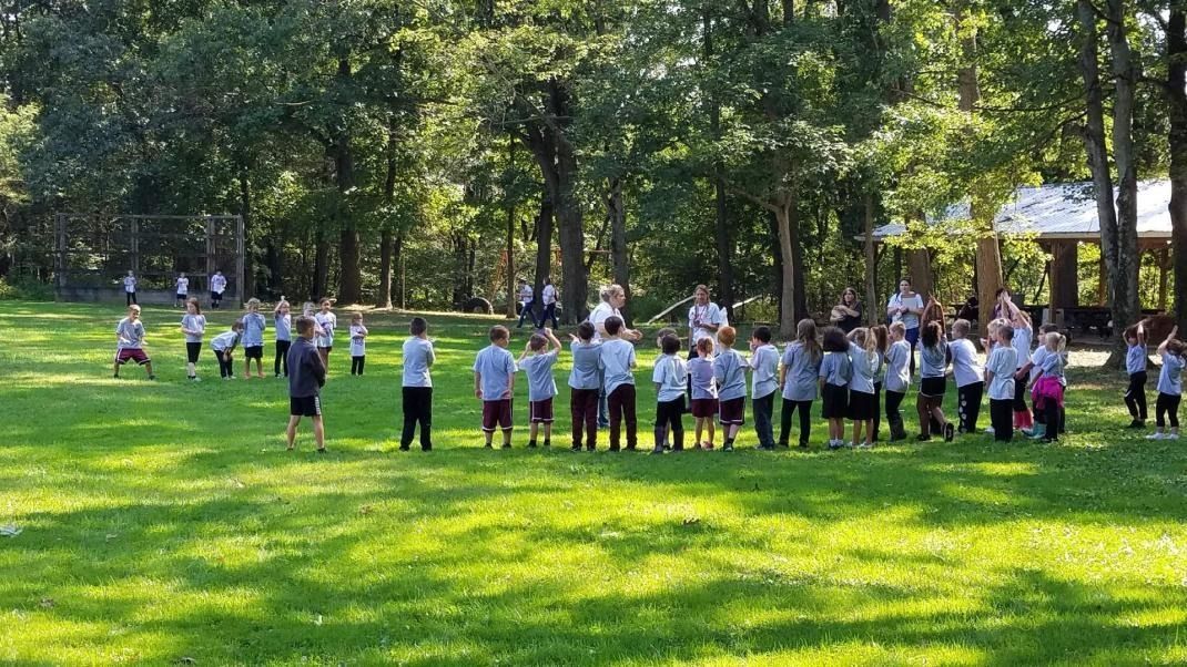 A group of children are standing in a circle in a grassy field.
