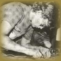 A black and white photo of a man working on a piece of wood.
