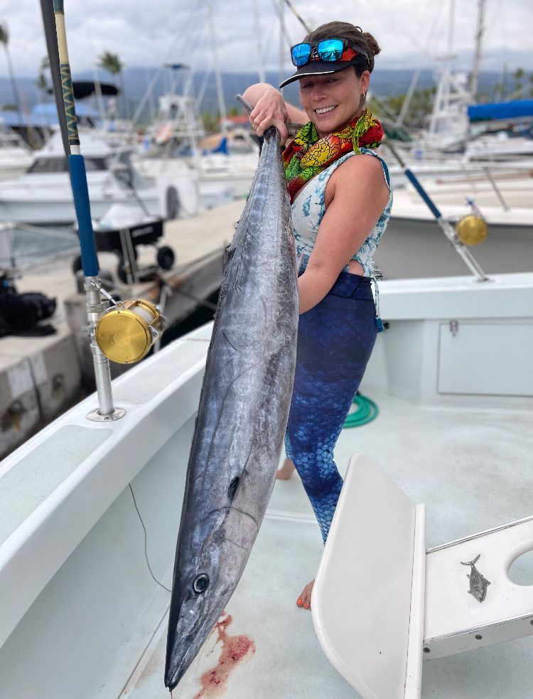 A man is standing on the deck of a boat holding a fish.