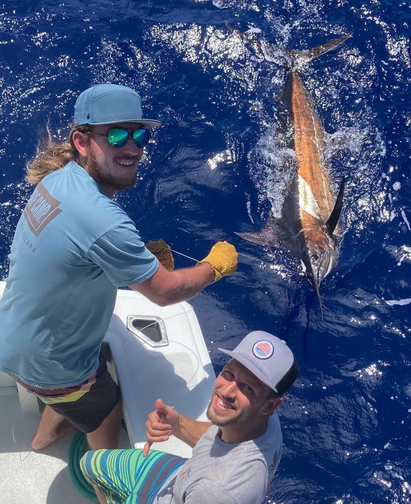 Two men are fishing on a boat in the ocean.