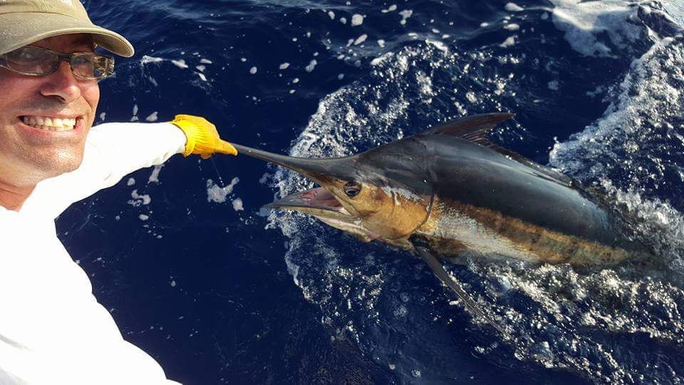 Two men are fishing on a boat and one has a hat that says viper on it