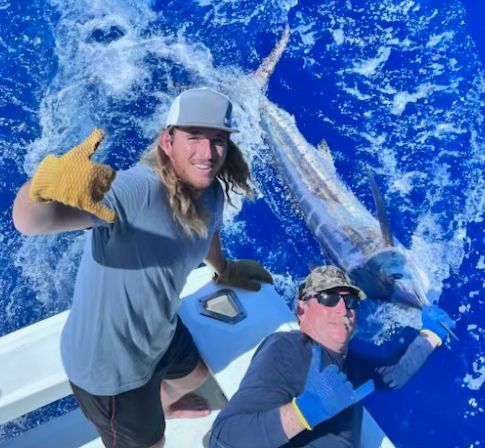 A man in a purple hat is fishing in the ocean